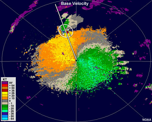 Base velocity image showing shades of green east of the radar and shades of orange west of the radar.  Further northwest from the radar, there is a small region of strong outbound velocities in red adjacent to a small region of strong inbound velocities in blue.