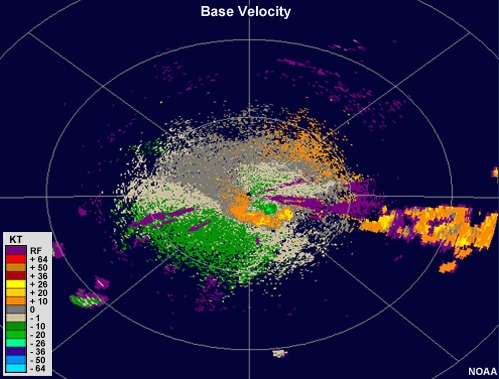 Radar velocity showing a large area of strong outbound velocities aligned with a cluster of thunderstorms, with an adjacent small region of strong inbound velocities that is slightly closer to the radar